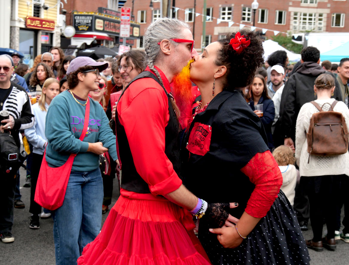 Members of Forward! Marching Band of Madison, Wisconsin, kiss at the Honk Festival, Sunday, Oct. 11, 2026. (©Greg Cook photo)
